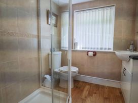 A bathroom with a shower enclosure toilet sink and a window with vertical blinds at Lynch Cottage in Rousdon