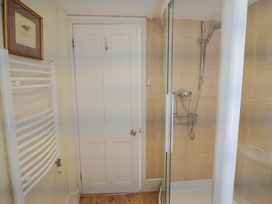 A bathroom with a shower enclosure a white door a white towel radiator and a framed picture on the wall at Lynch Cottage in Rousdon