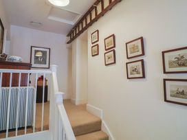 A staircase landing with framed pictures on the wall a wooden chest of drawers and a basket at Lynch Cottage in Rousdon
