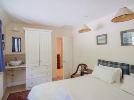 A bedroom with a double bed white wardrobe and a sink with mirror at Lynch Cottage in Rousdon