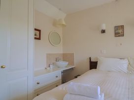 A bedroom with a bed a white sink on a countertop a round mirror and a closet at Lynch Cottage in Rousdon