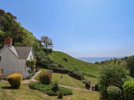 A white house with a garden on a hillside overlooking the sea at Lynch Cottage in Rousdon