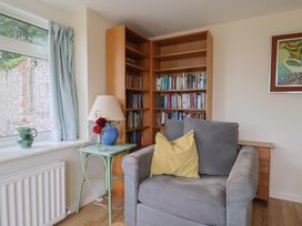 A living room with an armchair and bookshelf at Penny Plot Cottage in Lyme Regis
