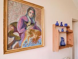 A painting and shelf with blue vases in a living room at Penny Plot Cottage in Lyme Regis