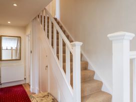 A hallway with a staircase and mirror at Barn Close Farm Morcombelake