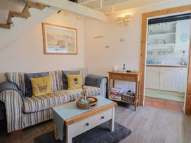 A living room with a sofa and kitchenette at Cleve Cottage in Lyme Regis