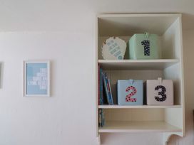 A shelf with storage boxes and books at Cleve Cottage in Lyme Regis