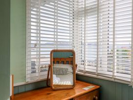 A bedroom with a mirror and window with blinds at 1 Wellhayes in Lyme Regis