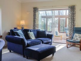 A living room with a blue sofa and glass door at High Cliff Orchard in Lyme Regis