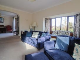 A living room with blue sofas and a piano at High Cliff Orchard in Lyme Regis