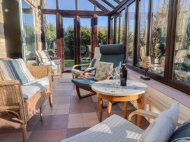 A conservatory with furniture and a wine bottle at High Cliff Orchard in Lyme Regis