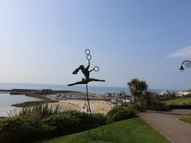 A view of a beach and marina with a sculpture at High Cliff Orchard in Lyme Regis