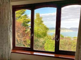 A window showing a view of trees and water at High Cliff Orchard in Lyme Regis