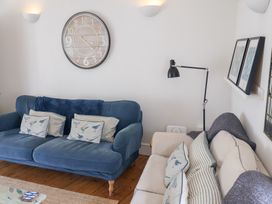 A living room with sofas, clock, and lamp at The Bakehouse in Lyme Regis