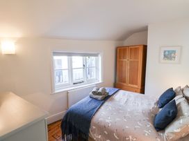 A bedroom with a bed, wardrobe, and window at The Bakehouse in Lyme Regis