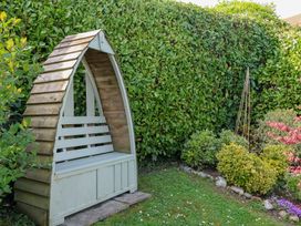 A wooden bench in a garden surrounded by greenery at The Bakehouse in Lyme Regis