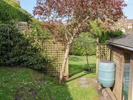 A garden with a tree and a water butt near a wooden structure at The Bakehouse in Lyme Regis