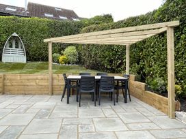 A garden with a wooden table and chairs under a pergola at The Bakehouse in Lyme Regis