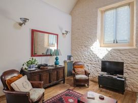 A living room with a sofa, coffee table, and TV at The Stone Barn in Bridport