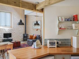 A kitchen and living room area with a sofa and television at The Stone Barn in Bridport
