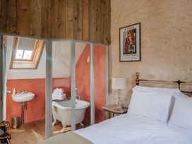 A bedroom with a bed and bath area at The Stone Barn in Bridport