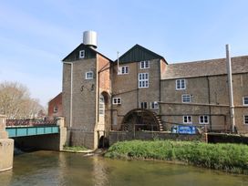A watermill with a bridge over a river at The Stone Barn in Bridport