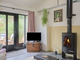 A living room with a television, wood stove, and basket at The Dairy in Bridport