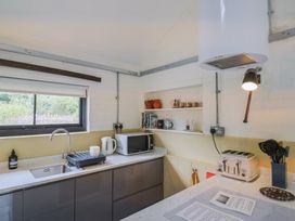 A kitchen with sink, microwave, toaster, and shelves at The Dairy in Bridport