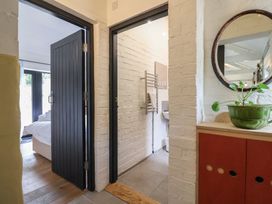 A hallway with a cabinet and doors leading to a bathroom and bedroom at The Dairy Bridport