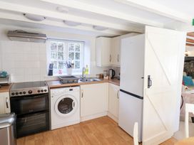 A kitchen with appliances including an oven, washing machine, refrigerator, and sink at The Gatehouse in Axmouth