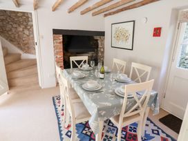 A dining room with a table set for six near a fireplace and stairs at The Gatehouse in Axmouth