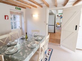 A dining area with a table set for six and a door leading to another room at The Gatehouse in Axmouth