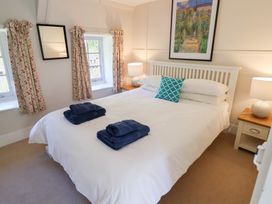 A bedroom with a white bed and blue towels on it two windows with curtains and a framed picture above the bed at The Gatehouse in Axmouth