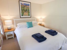 A bedroom with a white bed with blue towels and a blue cushion and bedside tables with lamps at The Gatehouse in Axmouth