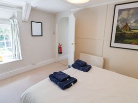 A bedroom with a bed with folded towels window and a painting on the wall at The Gatehouse in Axmouth