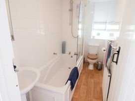 A bathroom with a bathtub toilet sink towel rail and wooden floor at The Gatehouse in Axmouth