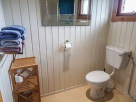 A bathroom with towels on a shelf and a toilet at 10 Pinewood Retreat in Pinewood