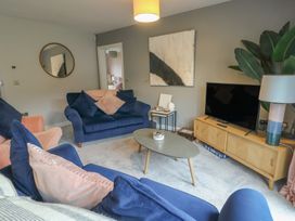 A living room with blue sofas and a coffee table at 11 Parc Delfryn in Brynteg near Benllech