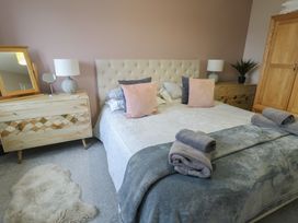 A bedroom featuring a bed with pillows and a nightstand at 11 Parc Delfryn Brynteg near Benllech