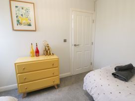 A bedroom with a yellow dresser, decorative items, and a bed at 11 Parc Delfryn Brynteg near Benllech
