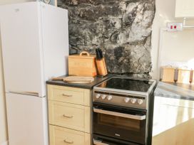 A kitchen corner with a white fridge a bread box a knife holder a stove and wooden drawers at Mews Cottage in Llanrwst