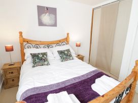 A bedroom with a double bed with floral cushions two bedside tables with lamps and a sliding door wardrobe at Mews Cottage in Llanrwst