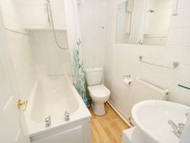 A bathroom with a bathtub a toilet a sink and a shower curtain at Mews Cottage in Llanrwst