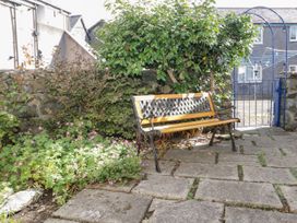 A garden area with a bench stone paving plants and a blue gate at Mews Cottage in Llanrwst