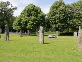 A grassy area with standing stones and trees in the background at Mews Cottage in Llanrwst