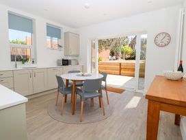 A kitchen with a round dining table and four chairs next to sliding glass doors leading to a garden at Flat 1 in Hunstanton