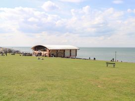 A grassy area with people sitting and walking near a building by the sea at Flat 1 in Hunstanton