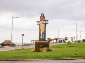 A roadside sign that says Hunstanton with a decorative panel and a coat of arms on a grassy area near the seafront at Flat 1 in Hunstanton