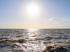 A view of the sea with the sun shining above and waves on the water at Flat 1 in Hunstanton