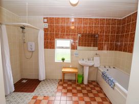 A bathroom with a shower, bathtub, sink, and a mirror at Forest View, Ballinskelligs, County Kerry